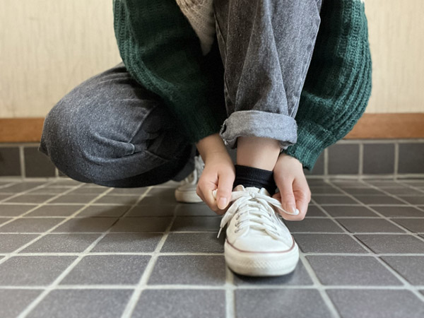 スニーカーのひもを結びなおしている写真。一度立ち止まって、もう一度自分のペースで歩き出す。そんな様子のイメージ。