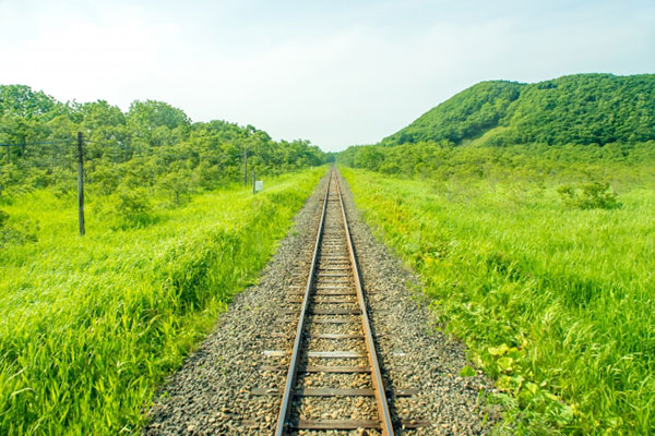 まっすぐ伸びた、明るい空の下のレールの写真。